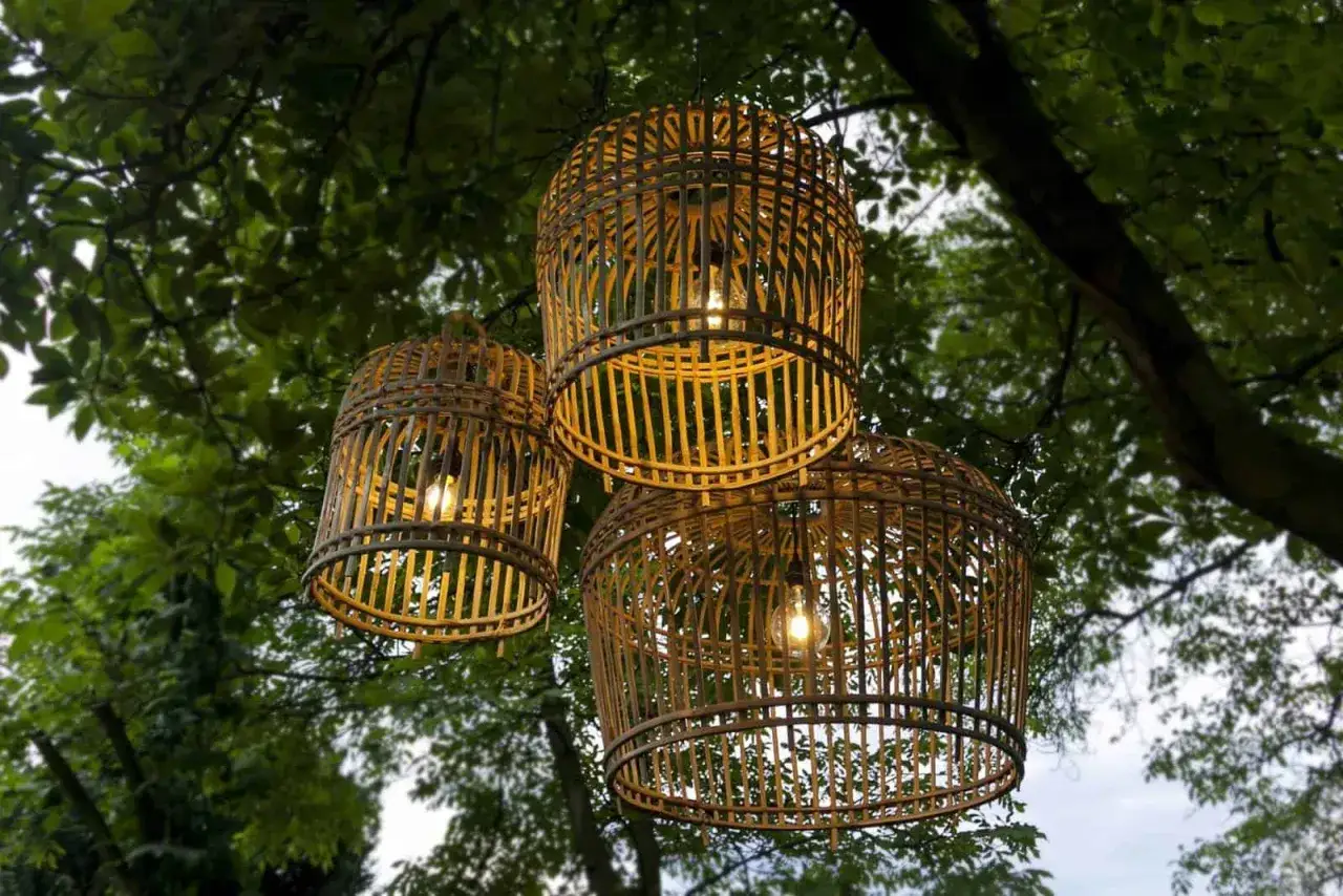 Trzy plecione lampy wiszące tworzą nastrojowe oświetlenie tarasu. Inspiracje naturalnym światłem i materiałami.