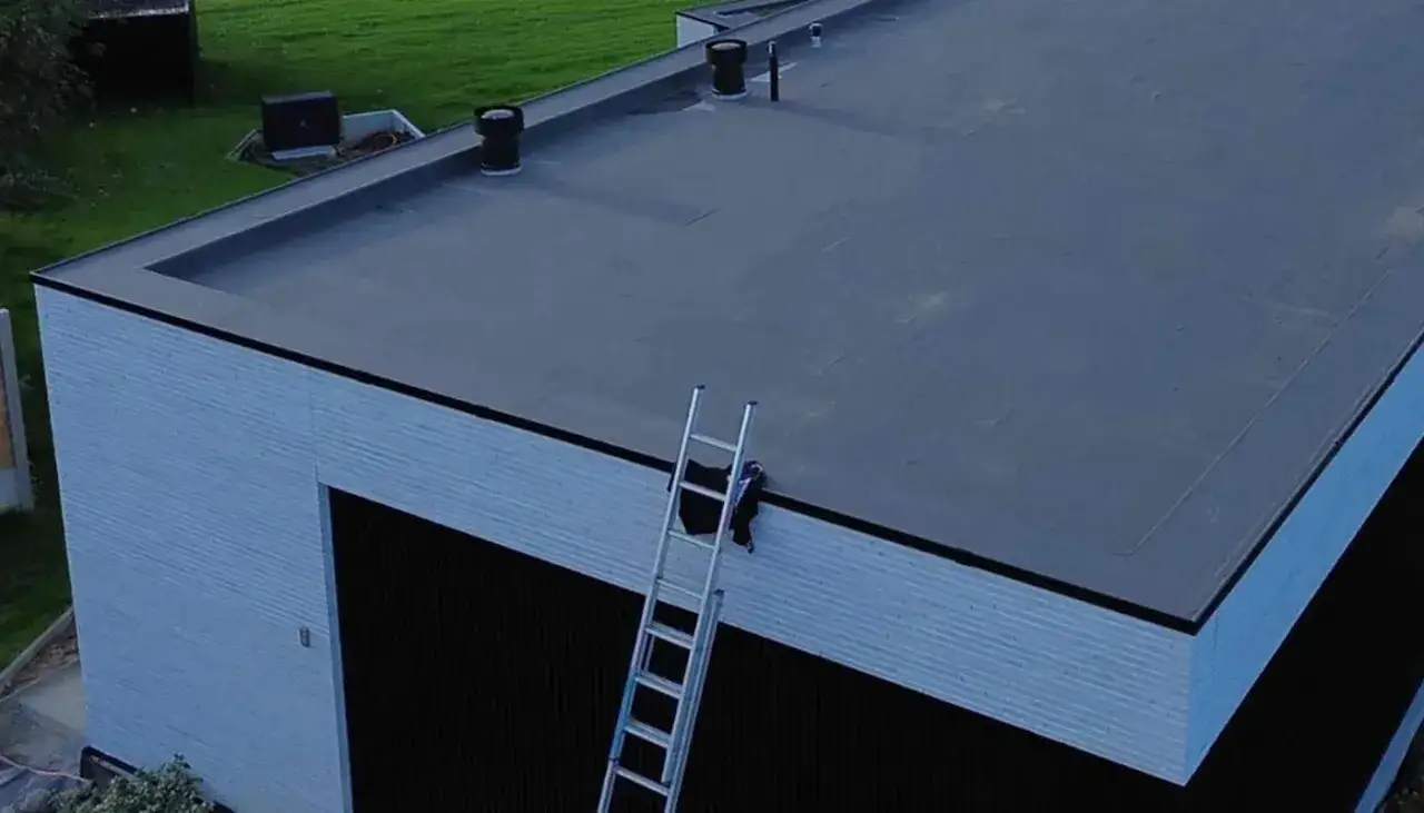 Płaski dach pokryty membraną EPDM, która jest trwała i odporna na warunki atmosferyczne. Na dachu drabina.