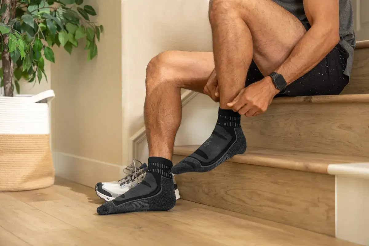 Mężczyzna zakłada ciemnoszare, sportowe skarpetki. Idealne, gdy zastanawiasz się, jakie skarpetki do biegania wybrać.