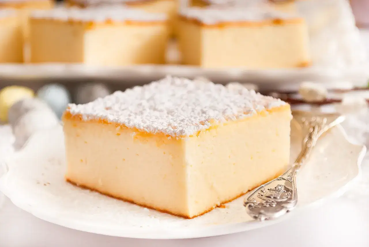 Puszysty sernik z budyniem, posypany cukrem pudrem, czeka na swój przepis. Idealny na deser.