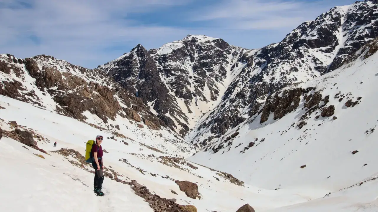 Wyprawa na Toubkal. Turystka z plecakiem na tle ośnieżonych g&oacute;r Atlas.