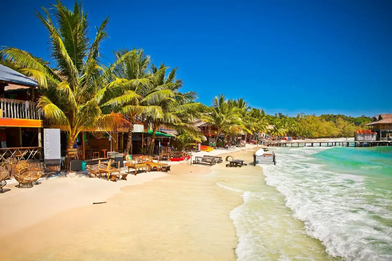 Rajska plaża na Koh Rong, Kambodża. Palmy, drewniane domki i turkusowa woda zapraszają do odpoczynku.