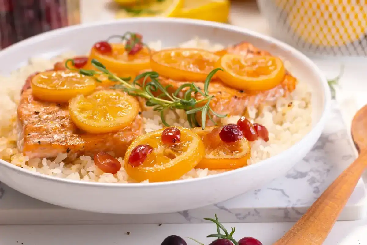 Soczysty łosoś na ryżu, udekorowany plasterkami cytryny i żurawiną. Aromatyczny posiłek, który zachwyca smakiem i wyglądem.