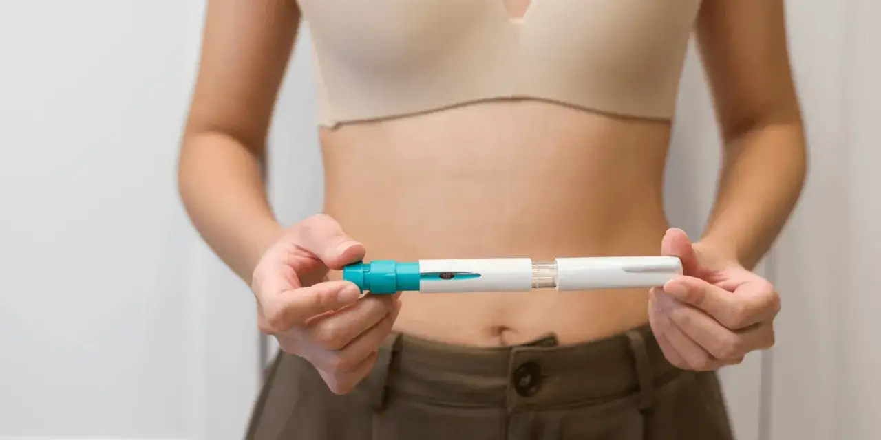 Kobieta trzyma w dłoniach wstrzykiwacz Ovitrelle. Po jego użyciu można sprawdzić, ile hcg po Ovitrelle jest w organizmie.