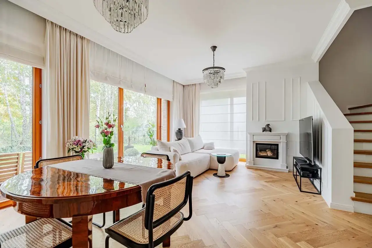 Elegancki salon z kominkiem i jadalnią, gdzie drewno i jasne tkaniny tworzą przytulny **country glam**.