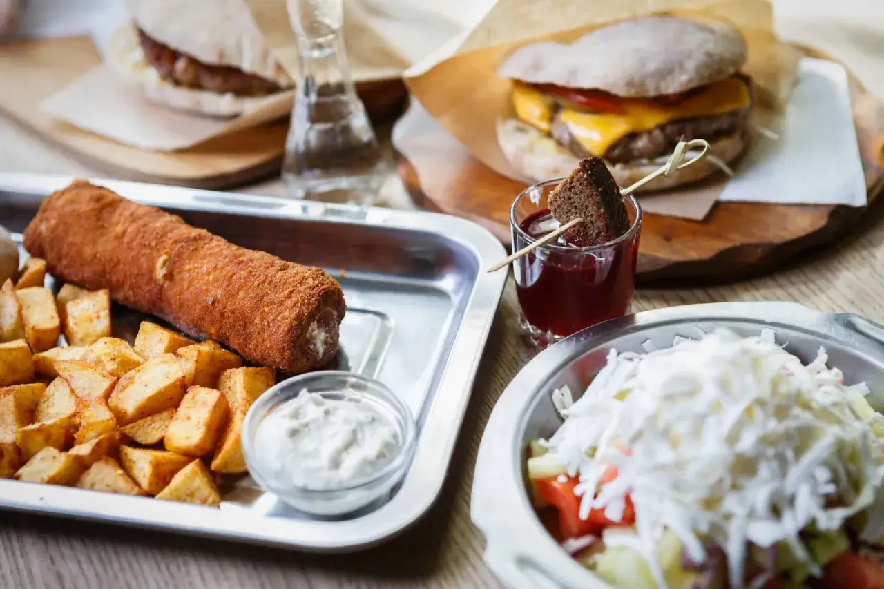 Sycące dania serbskie: panierowany roladek z ziemniakami, burger i sałatka.