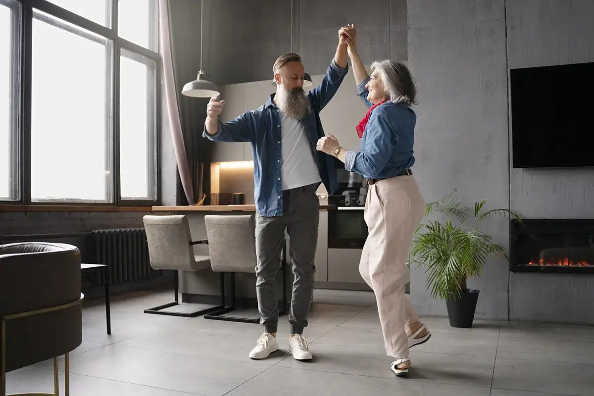 Para tańczy w salonie, ucząc się tańca w domu. Radosny wiecz&oacute;r pełen ruchu i wsp&oacute;lnej zabawy.