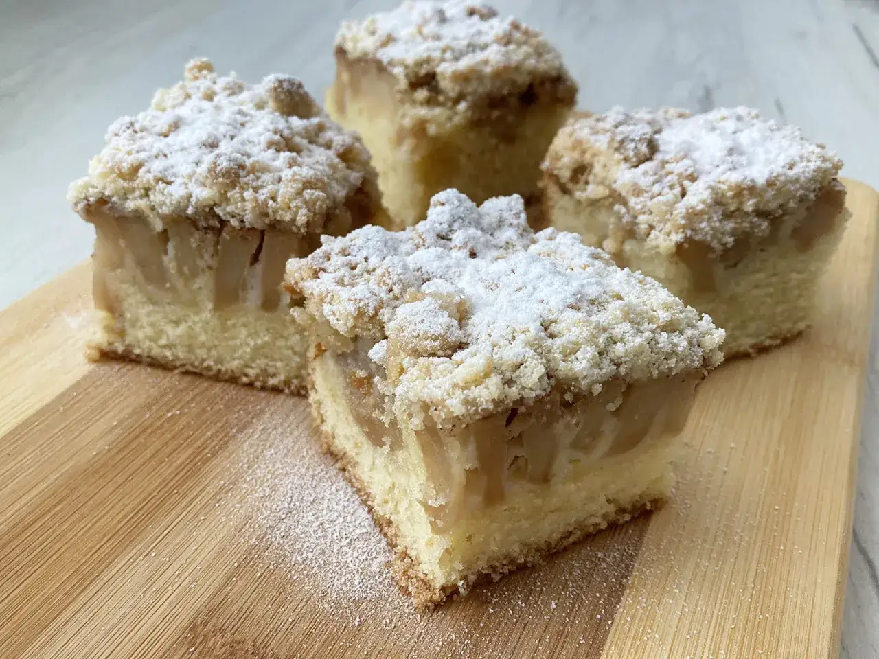 Szybkie ciasto na niedzielę do kawy: puszysty biszkopt z jabłkami i kruszonką, posypane cukrem pudrem. Idealne na leniwe popołudnie.