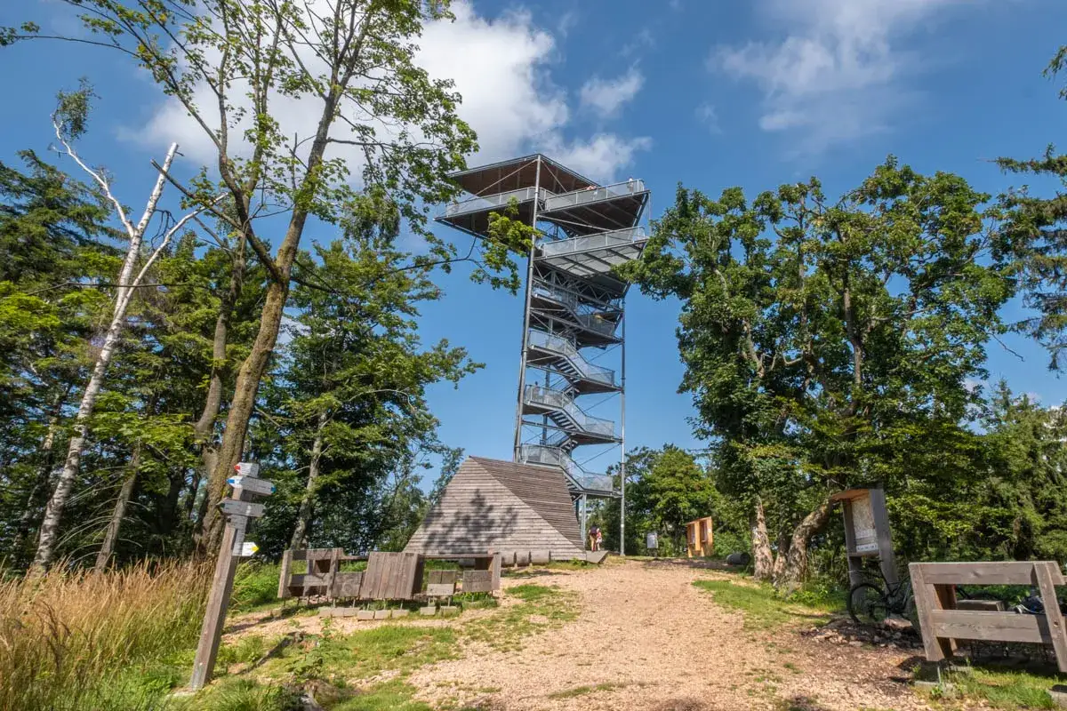 Wieża widokowa bac&oacute;wka pod Tr&oacute;jgarbem w otoczeniu zieleni, z drewnianą wiatą i ławkami.
