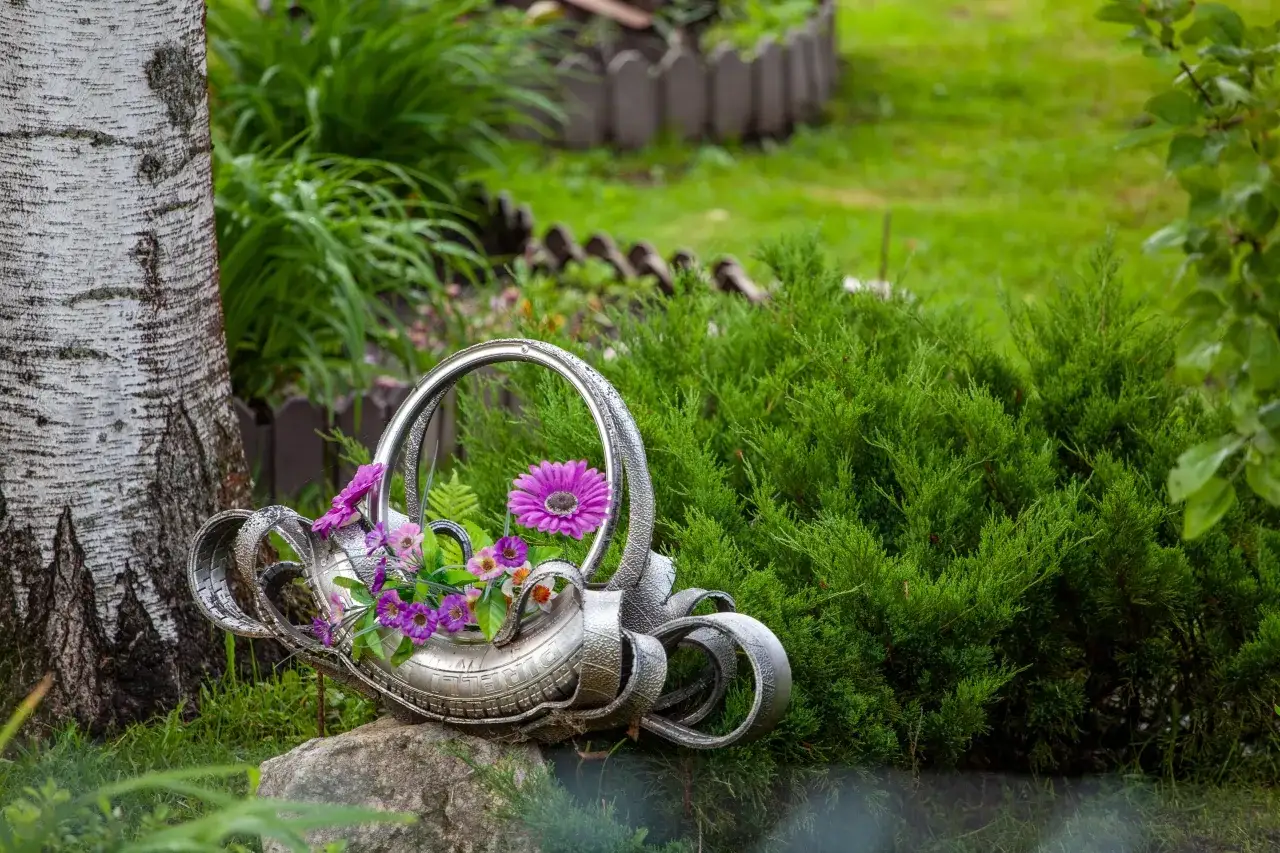 Opona do ogrodu przerobiona na oryginalny kwietnik z fioletowymi kwiatami.