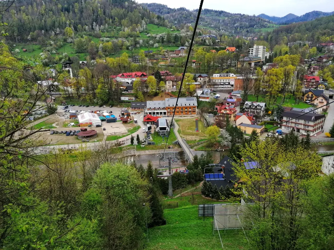 Widok na Palenicę, kurort narciarski, z kolejką linową i zielonymi wzgórzami.