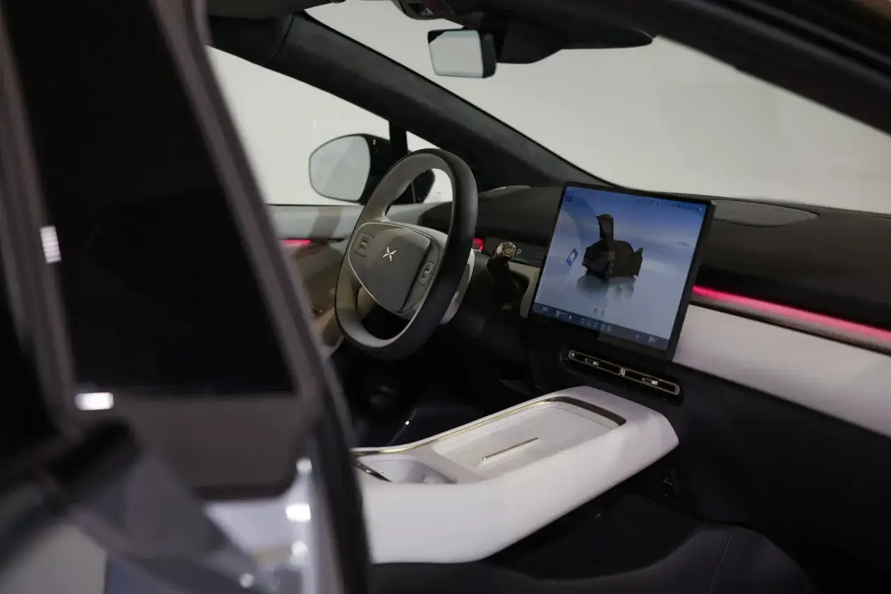 Wnętrze nowoczesnego samochodu elektrycznego. Kierownica, duży ekran dotykowy z wizualizacją auta i podświetlenie ambientowe. Jak ruszyć automatem pod górkę? Proste!