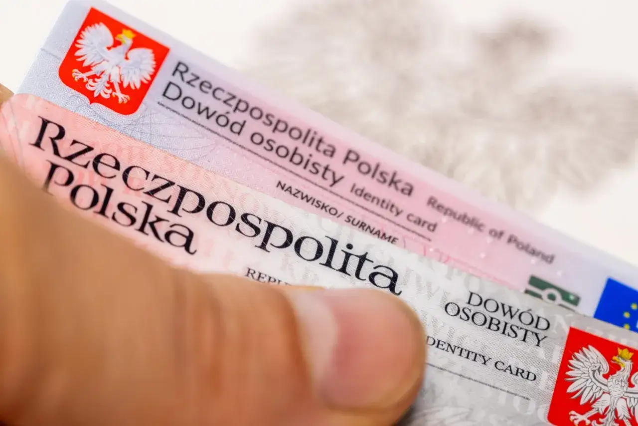 Dłoń trzyma polski dowód osobisty, symbolizujący anulowanie zastrzeżenia dowodu osobistego. Widoczny orzeł i napis 