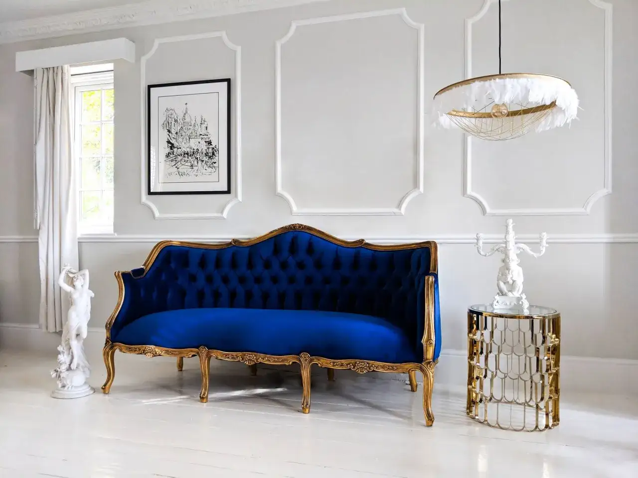 Elegancki salon w stylu paryskim z granatową sofą, złotymi zdobieniami i stylową lampą.