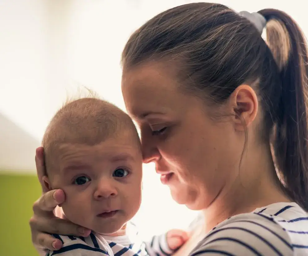 czułe zdjęcie rodzica przytulającego niemowlę