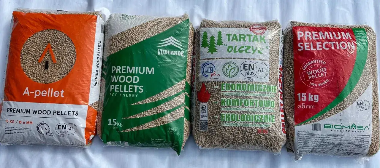 Cztery worki z pelletem drzewnym, w tym tani pellet z Czech. Widać różne marki i certyfikaty jakości.
