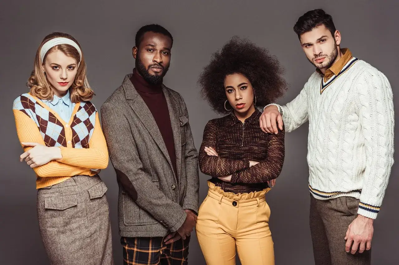 Cztery osoby prezentują styl retro ubrania: kobiety w kardiganach i spódnicach, mężczyźni w marynarkach i swetrach.