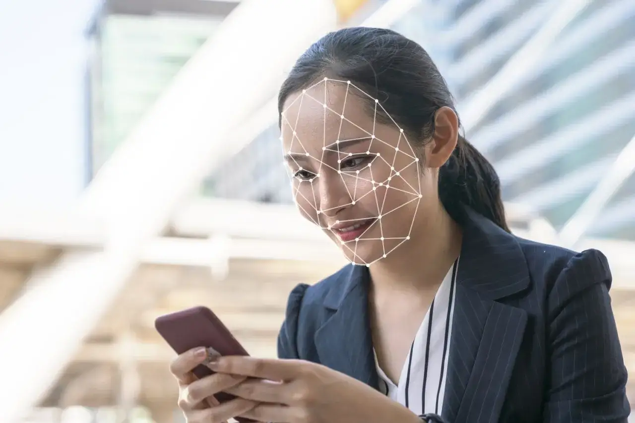 Kobieta z siatką na twarzy pokazuje, jak odblokować telefon przez aparat. Szybkie i bezpieczne rozpoznawanie twarzy.