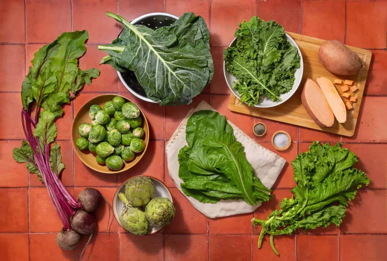 Bruksele, buraki, jarmuż, bataty i inne zielone warzywa z błonnikiem ułożone na ceglanej podłodze.