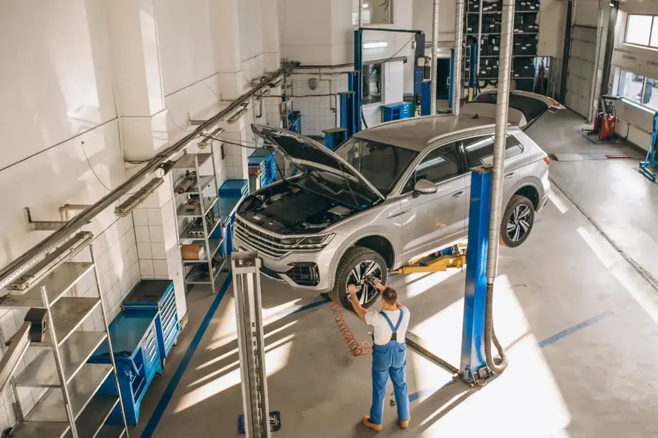 Mechanik przy samochodzie w leasingu, kt&oacute;ry jest na podnośniku. Rozważasz naprawa samochodu w leasingu a koszty?