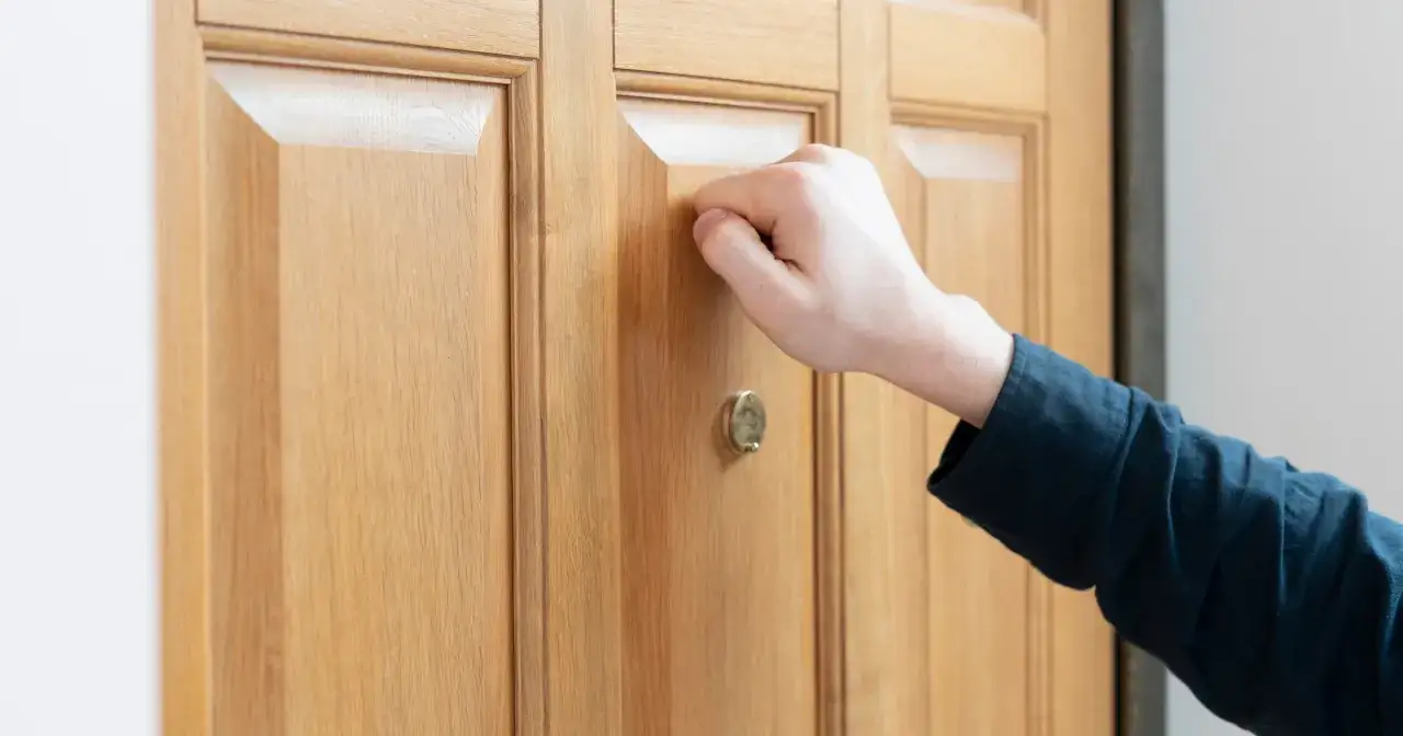 Dłoń puka do drzwi. Czy pracodawca może kontrolować pracownika na L4?