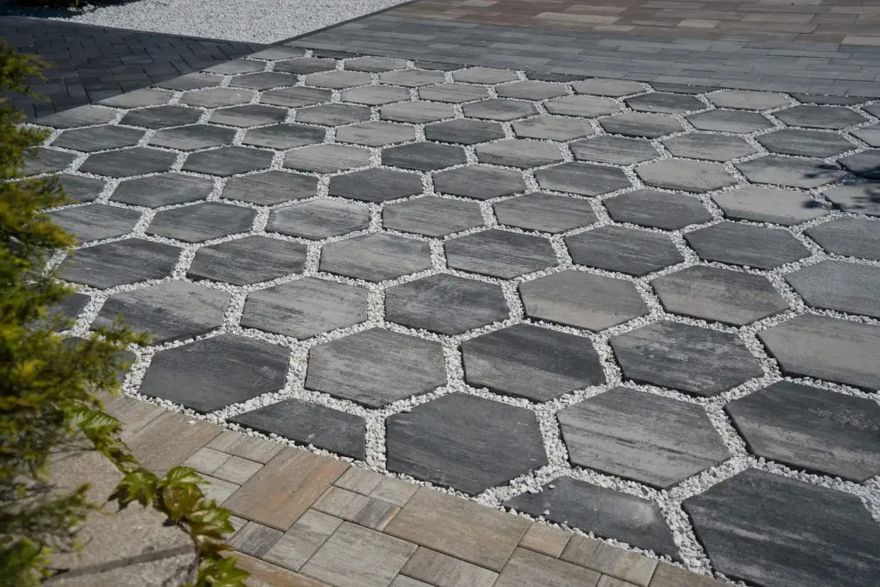 Nowoczesna kostka brukowa przed domem w kształcie plastra miodu, wypełniona białym żwirem. Inspiracje dla Twojego ogrodu.
