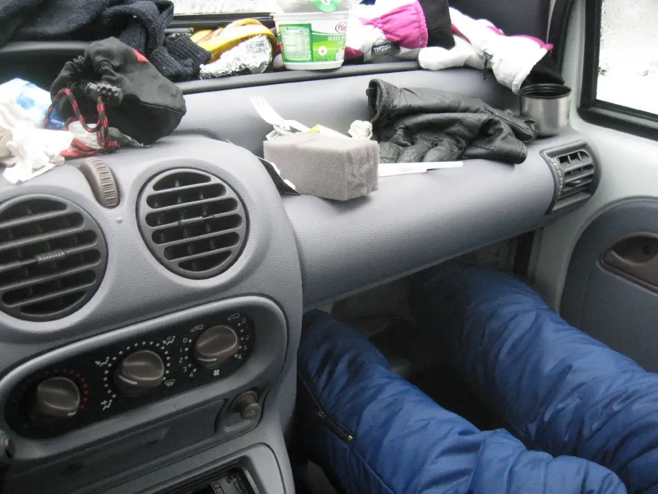 Wnętrze samochodu, przygotowane do spania w trasie po Europie. Na desce rozdzielczej leżą rękawiczki, kubek i inne drobiazgi.
