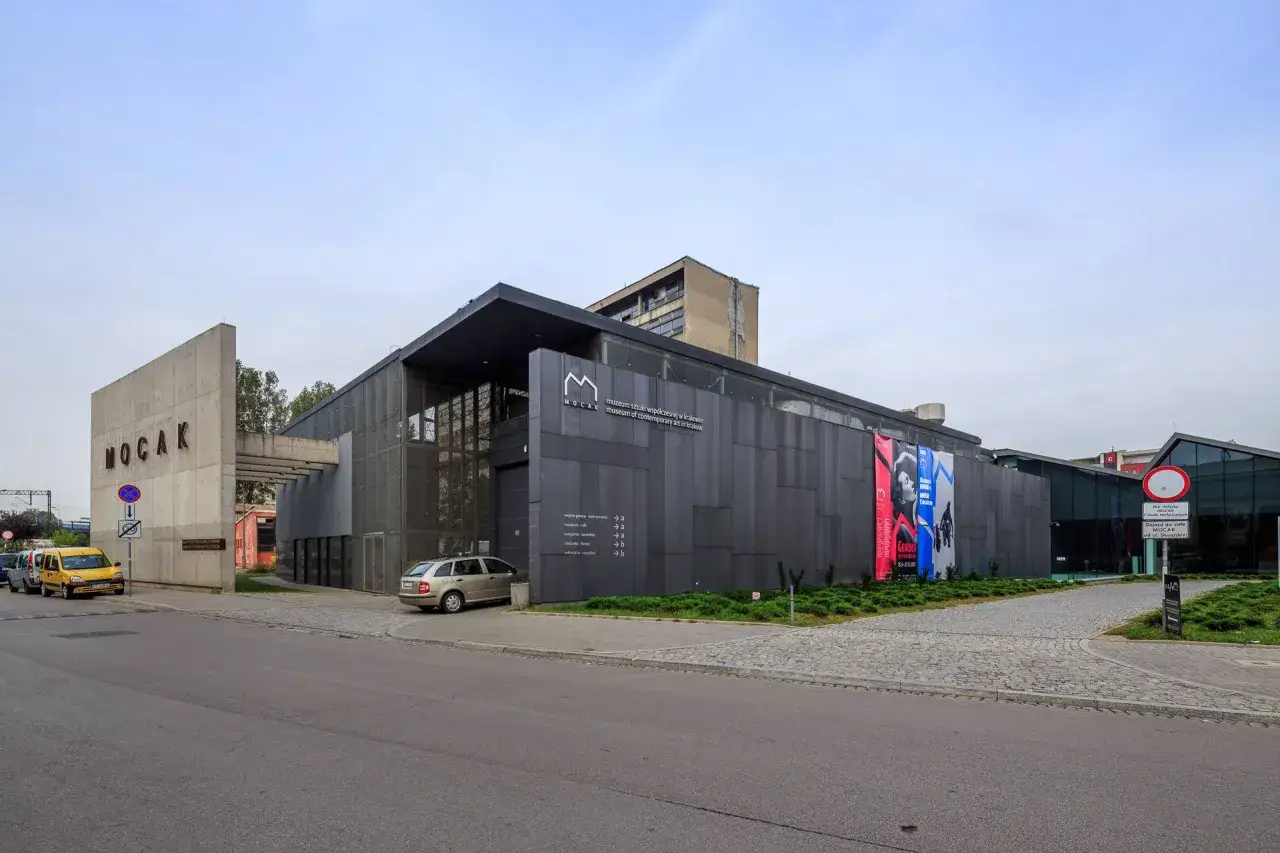 Nowoczesny budynek MOCAK Muzeum Sztuki Wsp&oacute;łczesnej w Krakowie z betonowym napisem i szarymi panelami.