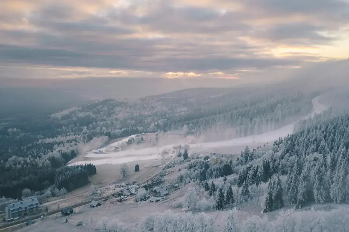 Mglisty poranek nad zimową wioską, od kiedy otwarte stoki narciarskie przyciągają miłośników białego szaleństwa.