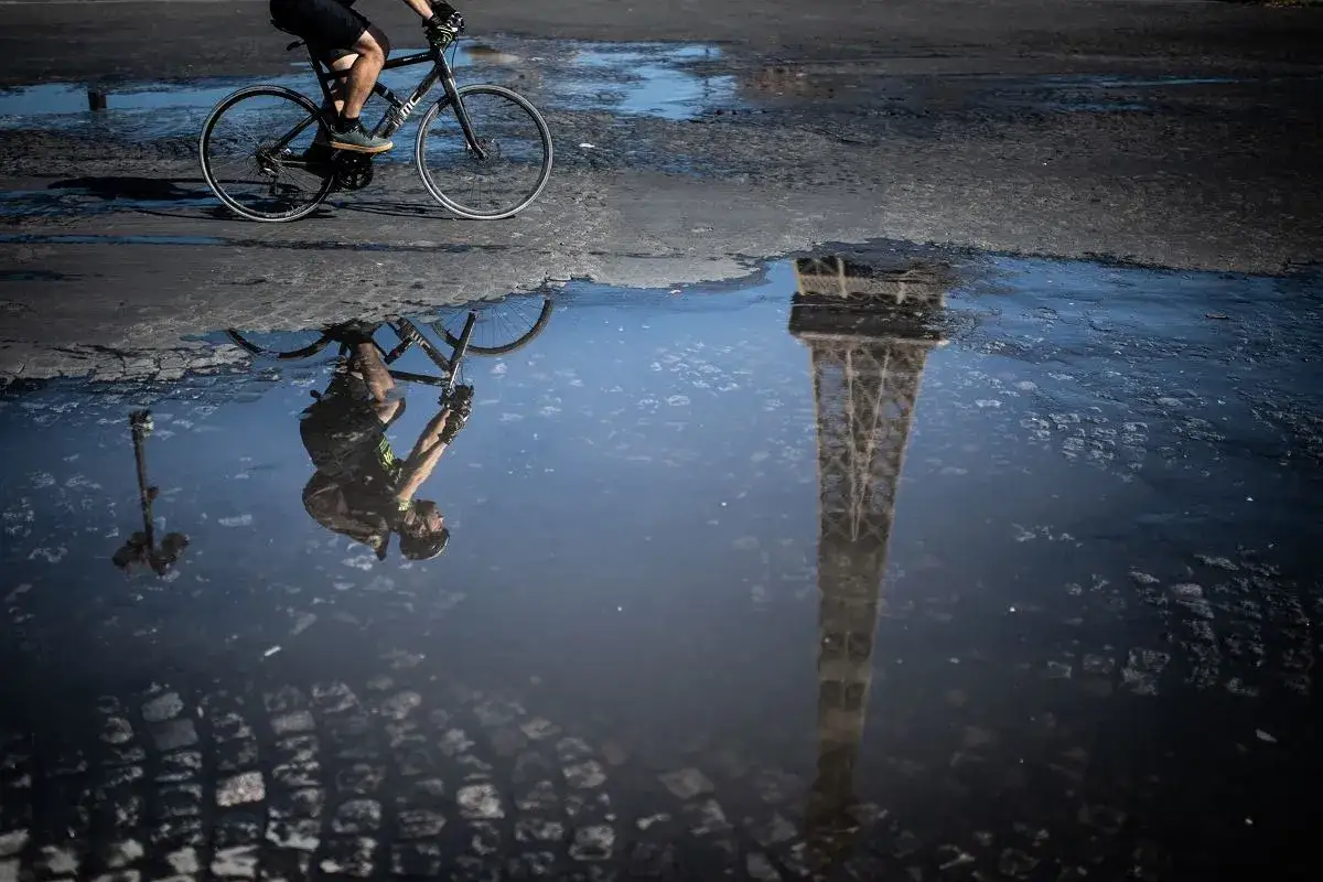 Rowerzysta w odbiciu kałuży widzi Wieżę Eiffla. To jedne z wielu plus&oacute;w jazdy na rowerze &ndash; odkrywanie świata w nieoczekiwany spos&oacute;b.