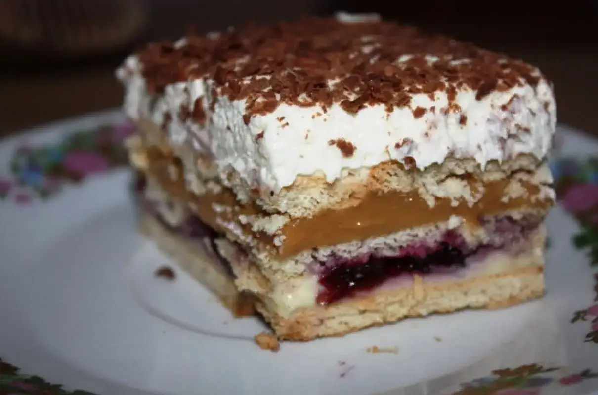 Pyszne ciasto bez pieczenia tanie, warstwowe z kremem, owocami i bitą śmietaną, posypane czekoladą.