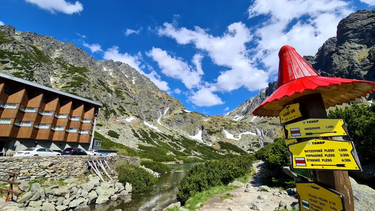 Piękne widoki w Tatrach Słowackich, od kiedy otwarte szlaki w tatrach słowackich, zachęcają do wędr&oacute;wek. Hotel i strumień u podn&oacute;ża g&oacute;r.