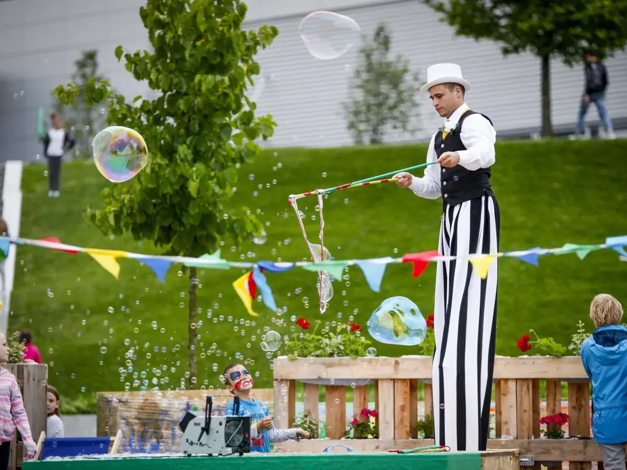 Pokaz baniek mydlanych na pikniku szkolnym to świetny pomysł na zabawę dla dzieci. Artysta w cylindrze tworzy tęczowe bańki, a maluchy z uśmiechem na twarzach obserwują magię.