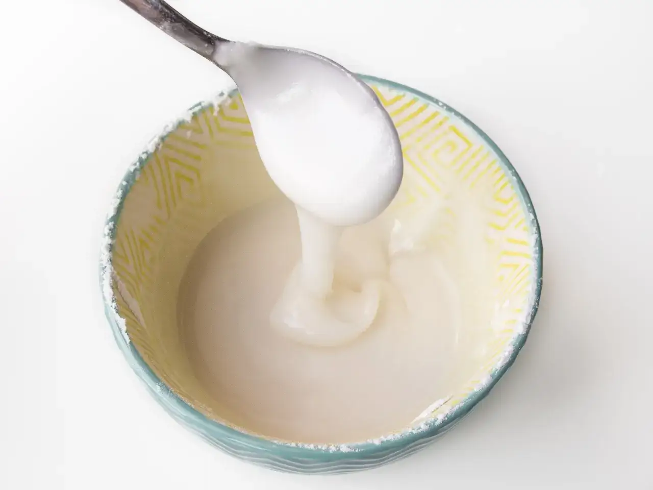 Łyżka z gęstym lukrem, kt&oacute;ry właśnie przygotowano, pokazując, jak zrobić lukier ze zwykłego cukru.