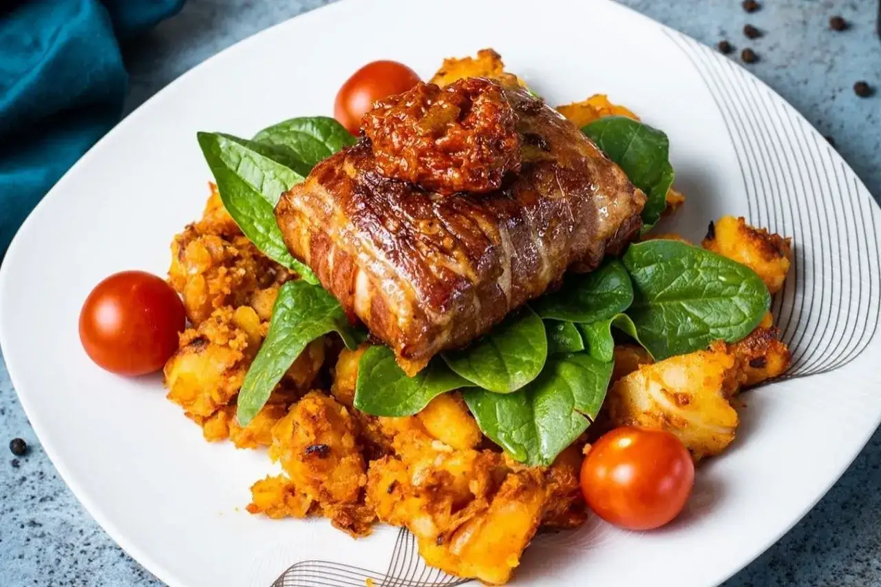 Mięso zawinięte w boczek, podane na ziemniakach z pomidorami i szpinakiem. Prawdziwy smak kuchni bałkańskiej.