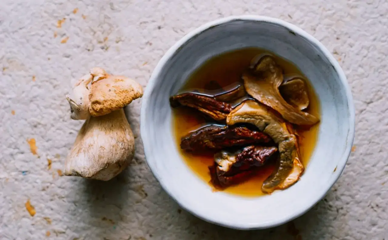 Świeży borowik obok miseczki z namoczonymi suszonymi grzybami. Zastanawiasz się, jak długo gotować suszone grzyby?