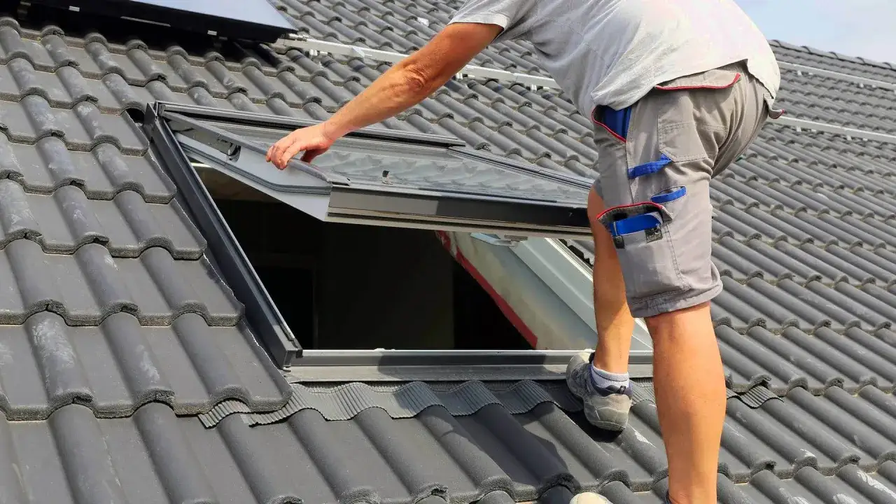 Pracownik montuje okno dachowe. Zastanawiasz się, ile kosztuje montaż okna dachowego?