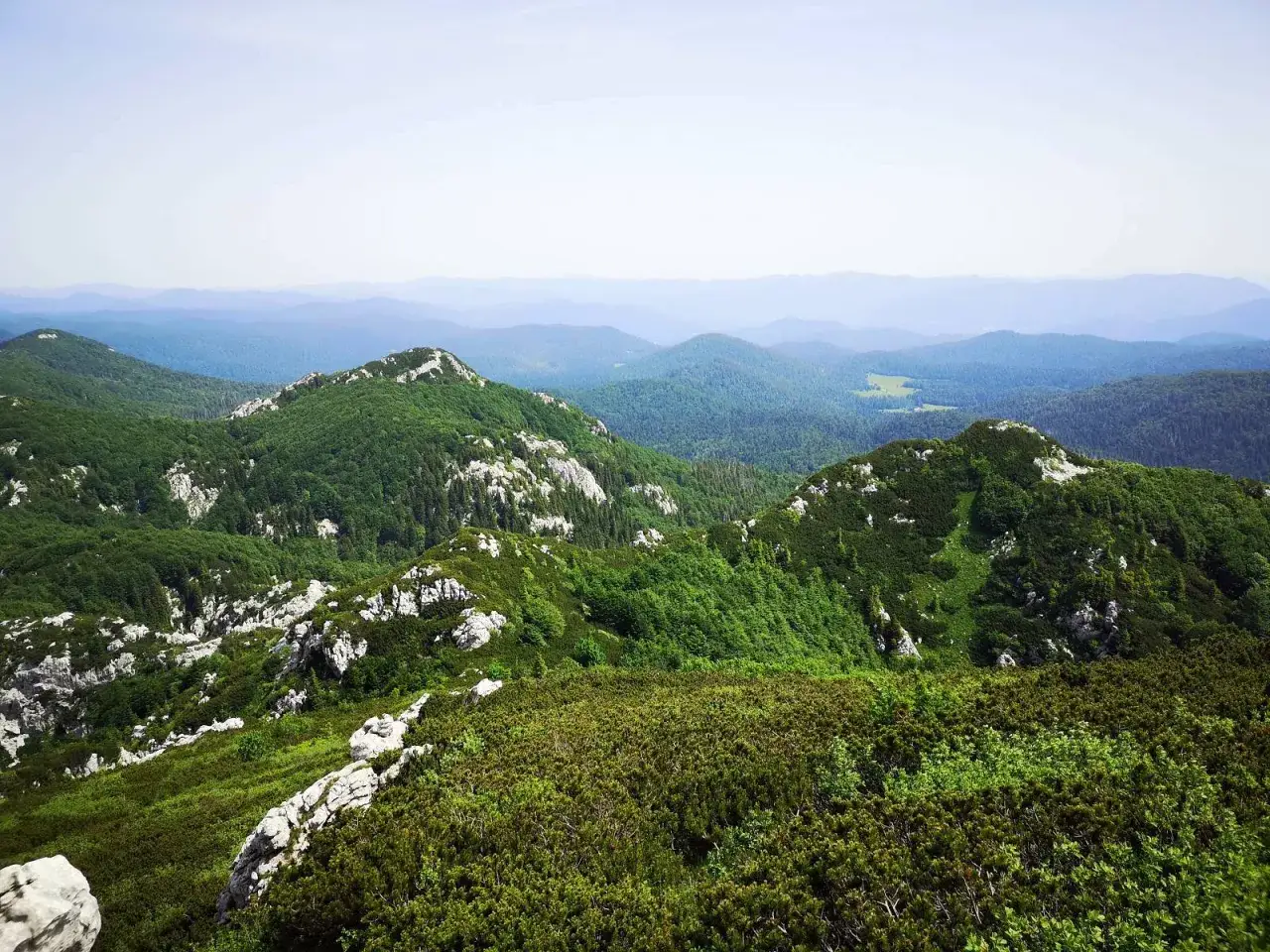 Widok na zielone, skaliste wzg&oacute;rza Chorwacji. W oddali widać kolejne pasma g&oacute;rskie, a na pierwszym planie gęste zarośla. To krajobraz najwyższego szczytu w Chorwacji.