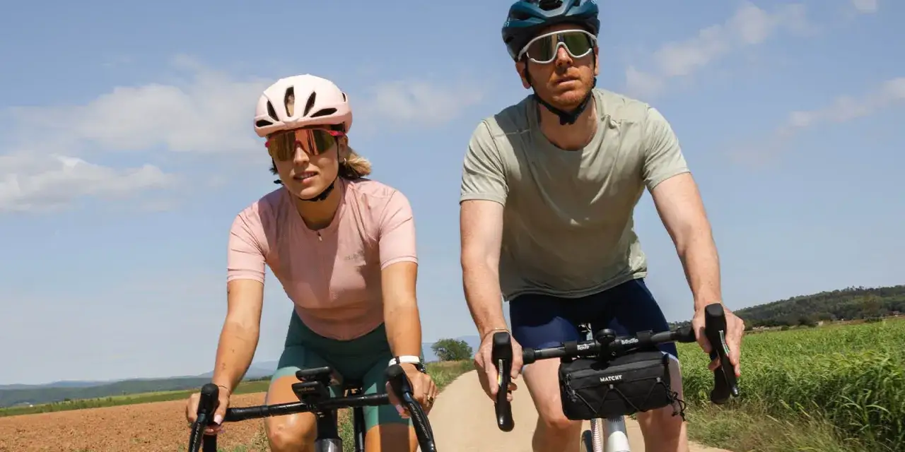 Para rowerzyst&oacute;w w kaskach i okularach przeciwsłonecznych, idealnych na rower. Ona ma r&oacute;żowy, on zielony str&oacute;j.