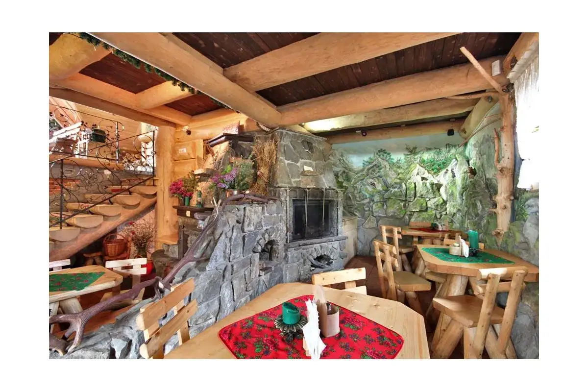 Przytulna restauracja w Bukowinie Tatrzańskiej z kamiennym kominkiem, drewnianymi meblami i g&oacute;ralskim klimatem.