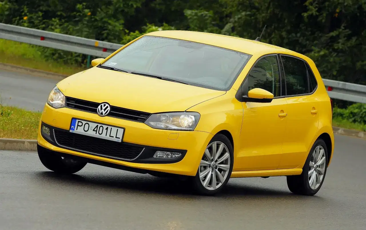 Żółty Volkswagen Polo na mokrej drodze. Poznaj polo dane techniczne tego miejskiego auta.
