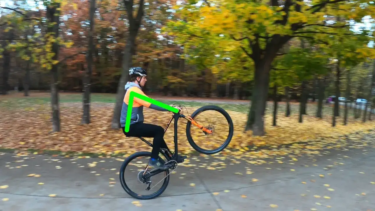 Chłopak ćwiczy jazdę na jednym kole rowerem w parku jesienią.
