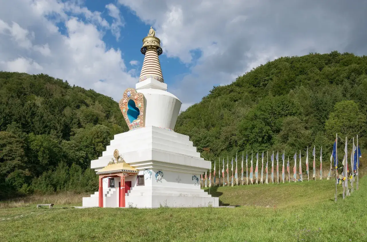 Biała stupa buddyjska na tle zielonych wzgórz. W Polsce jest niewielu buddystów, ale takie miejsca jak to świadczą o ich obecności.