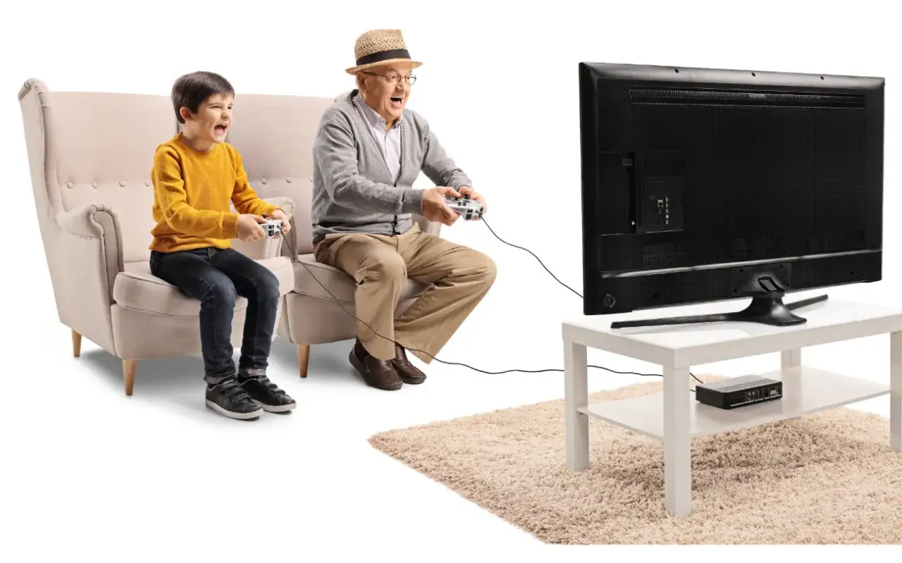 Dziadek i wnuk grają w gry logiczne dla senior&oacute;w darmowe, świetnie się bawiąc przed telewizorem.