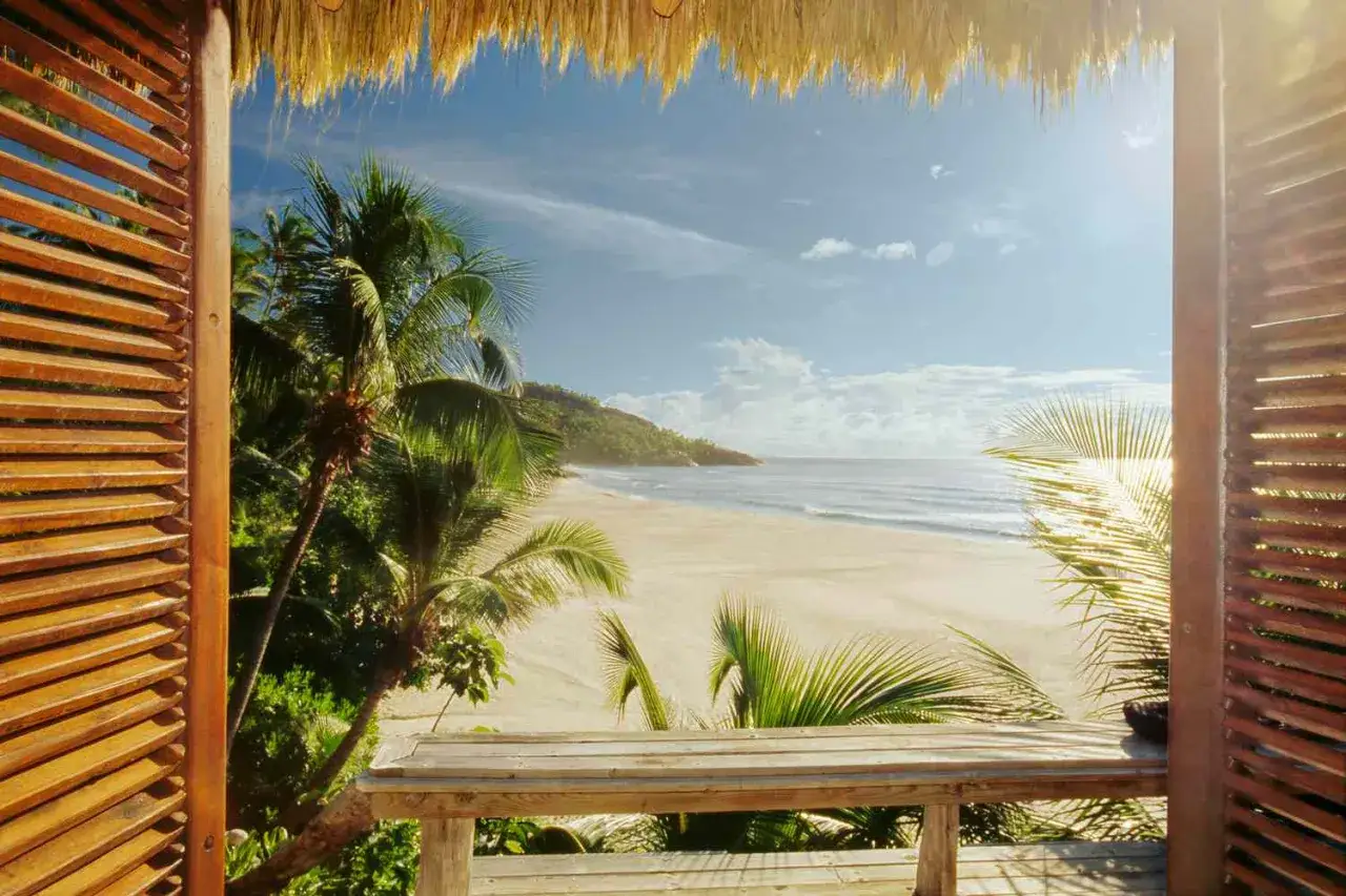 Widok z drewnianej werandy na rajską plażę z palmami. Czy to Seszele czy Malediwy?