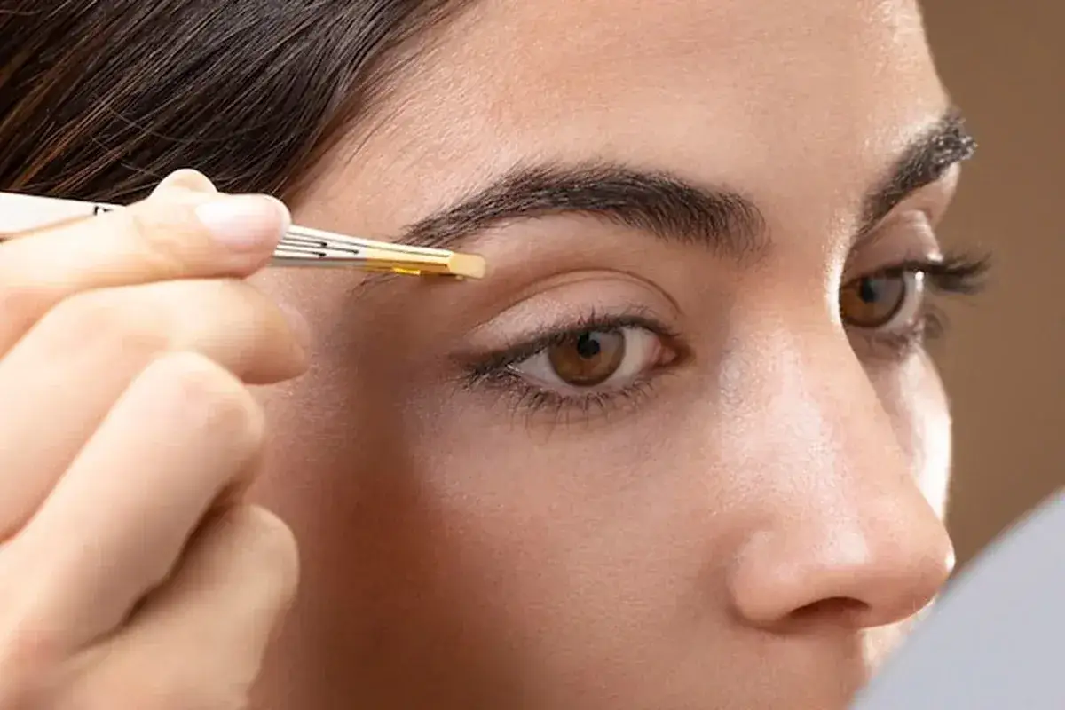 Kobieta aplikuje produkt do brwi, co jest częścią zabiegu laminacji brwi. Efekt: idealnie ułożone włoski.
