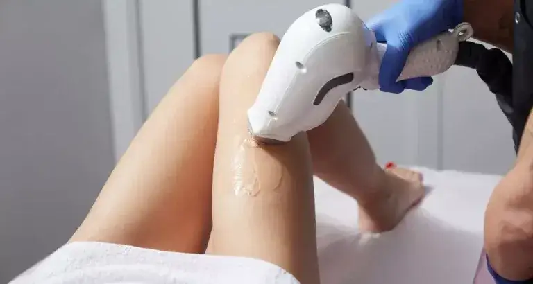 Kobieta goli nogi maszynką przed depilacją laserową