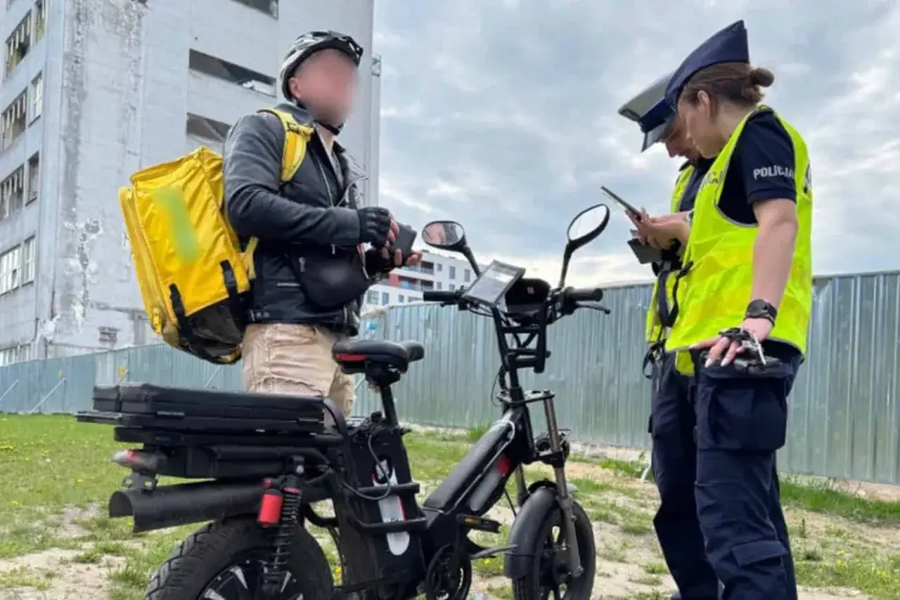 Dostawca z żółtą torbą i rower elektryczny bez pedałowania zatrzymany przez policję.