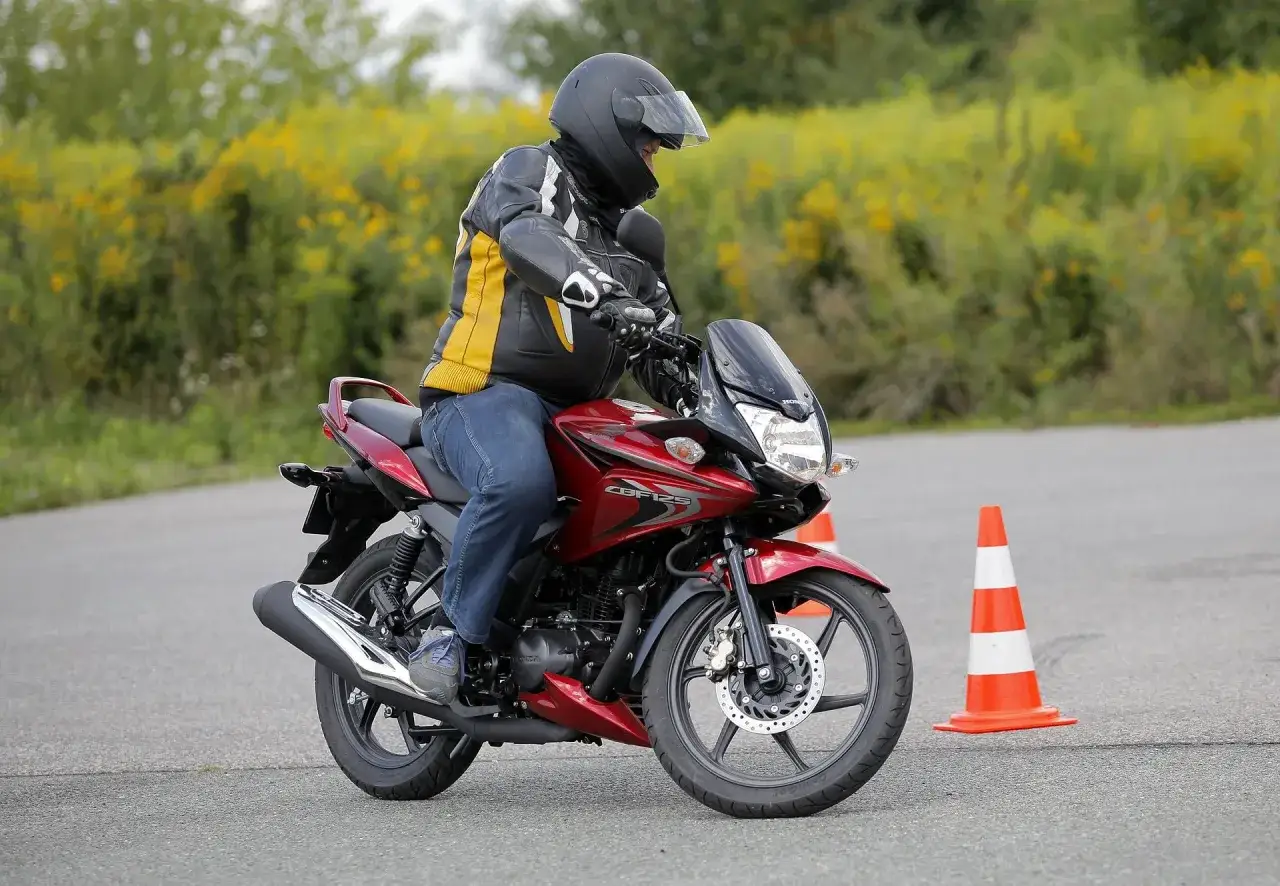 Jazda na czerwonym motocyklu Honda CBF125, w kasku i kurtce, podczas szkolenia z kategorii na motor.