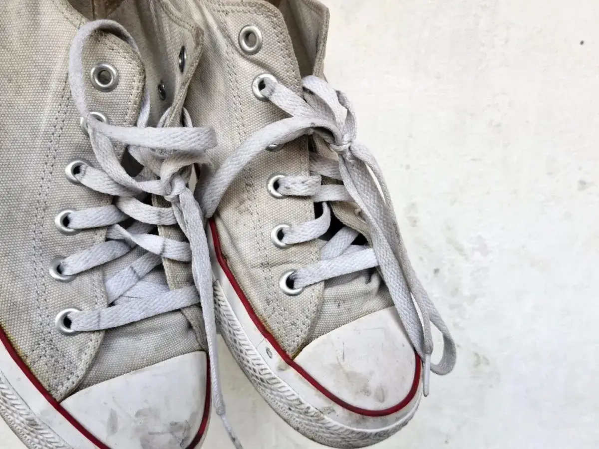 Brudne, białe trampki Converse czekają na pranie w pralce. Jak prać conversy w pralce, by znów były jak nowe?